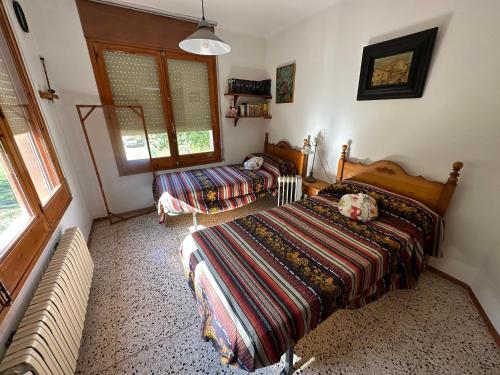 1 dormitorio con 2 camas y ventana en Casa Trianó entre montañas, río y cielo de estrellas, en Albanya