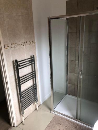 a shower with a glass door in a bathroom at Room in town centre in Saint Helens