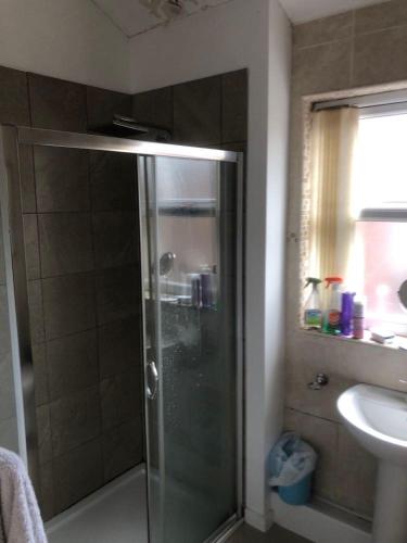 a shower with a glass door in a bathroom at Room in town centre in Saint Helens