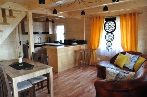Raków的住宿－Domki letniskowe Balia sauna Leśny Czar，厨房以及带桌子和沙发的客厅。