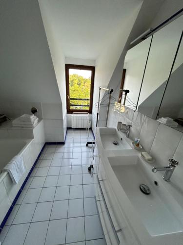 een witte badkamer met 2 wastafels en een raam bij Une chambre au Pré des fées in Salbris
