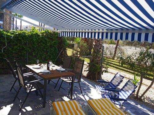 a table and chairs under a blue and white umbrella at Casa Algar - La Calma - big terrace - 4 pools in Playa Flamenca