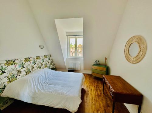 a bedroom with a bed and a mirror and a table at L'Herboriste - Appartements meublés in Gien