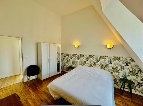 a bedroom with a white bed with a floral wall at L'Herboriste - Appartements meublés in Gien