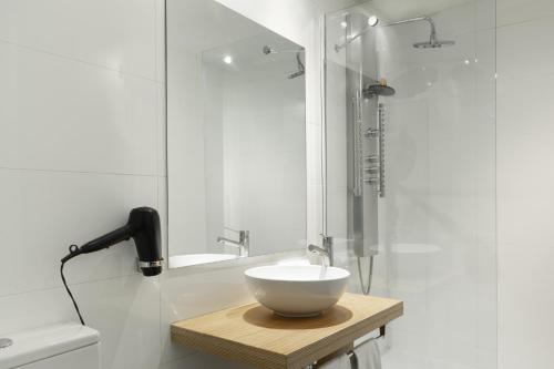 a bathroom with a white bowl on a wooden table at Petit Palace Tres Cruces in Madrid