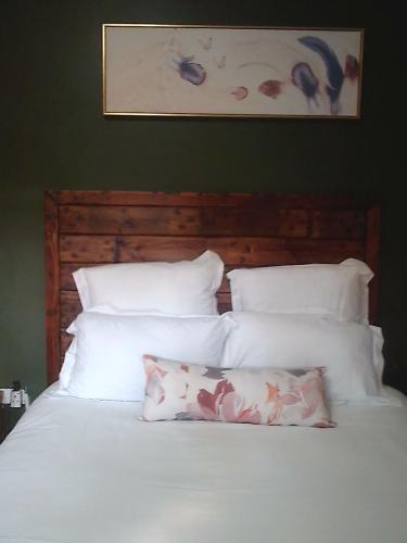 a bed with white pillows and a picture on the wall at Birdville BNB Guest House in Gaborone