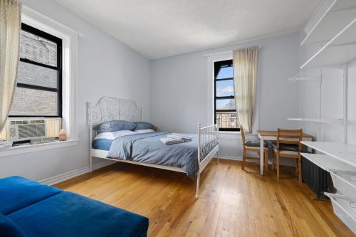 a bedroom with a bed and a desk and two windows at Live Upper Manhattan on a Budget in New York