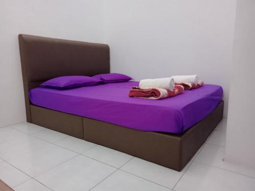 a bed with purple sheets and purple pillows at Wany Homestay Free Wifi And Astro NJOI in Sungai Petani