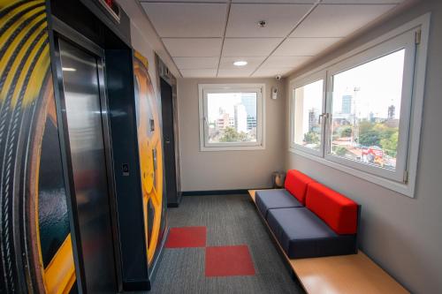 a waiting room with a red couch and two windows at ibis Asuncion in Asuncion