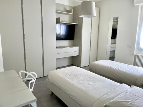 Habitación blanca con 2 camas y TV. en Domus Pyrus Apartments, en Pero