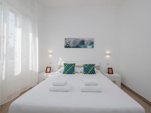 ein weißes Schlafzimmer mit einem großen weißen Bett mit blauen Kissen in der Unterkunft [IHost Apartment] - Rogoredo 27 in Mailand