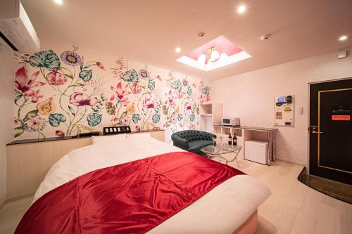 Cette chambre comprend un lit avec des draps rouges et du papier peint floral. dans l'établissement Hotel　このへんのアジア, à Kyoto