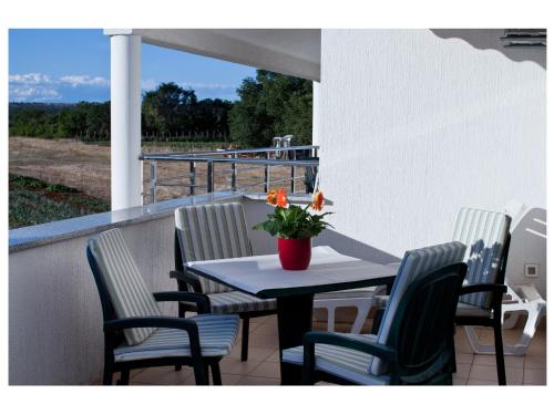 a table with chairs and a vase with flowers on a balcony at Apartments Moderno 2 in Fažana