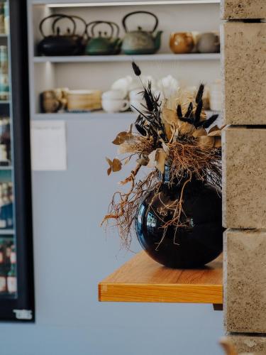 a black vase filled with dried flowers on a wooden shelf at Levy's Rooms & Breakfast in Salzburg