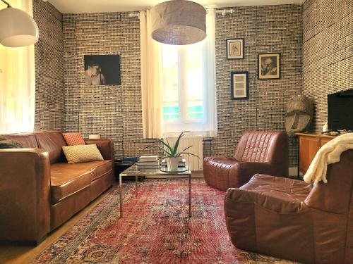 sala de estar con sofás de cuero y mesa en Les Colibris - Standing et Montagnes - 3 étoiles, en Cluses
