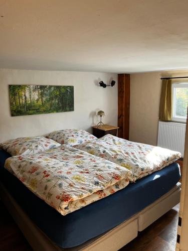a bedroom with a bed with a floral comforter at Wohnen auf dem Bauernhof in Herdecke
