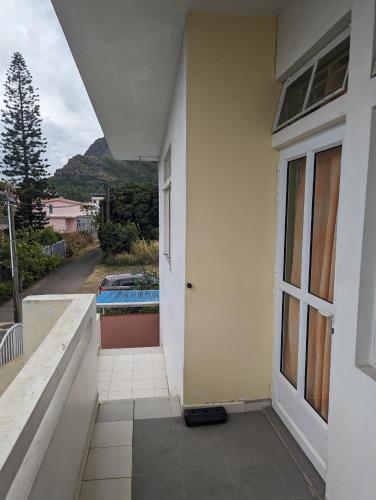 uma casa branca com uma porta e uma varanda em Appartment in residential area em Quatre Bornes