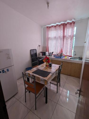 uma cozinha com uma mesa e cadeiras e um frigorífico em Appartment in residential area em Quatre Bornes