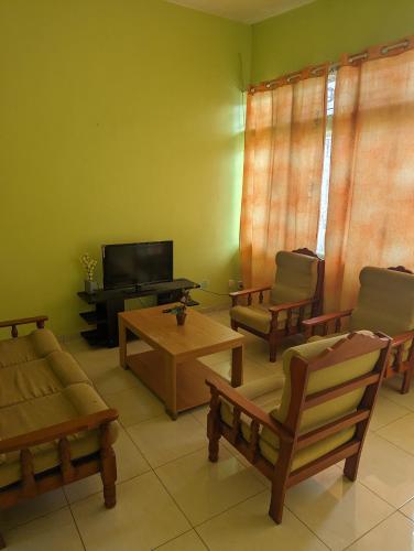 uma sala de estar com mobiliário em madeira e uma televisão de ecrã plano em Appartment in residential area em Quatre Bornes