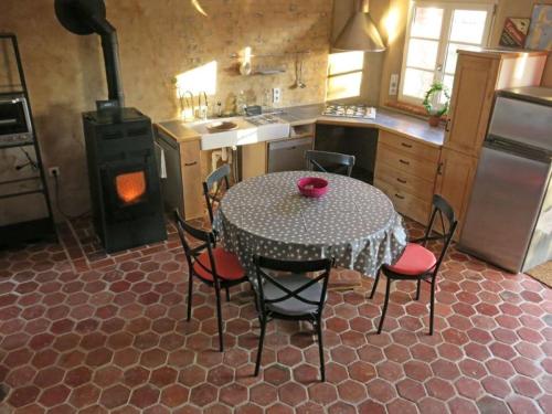 a kitchen with a table with chairs and a stove at Le Coq à l'Ane in Beaubec-la-Rosière