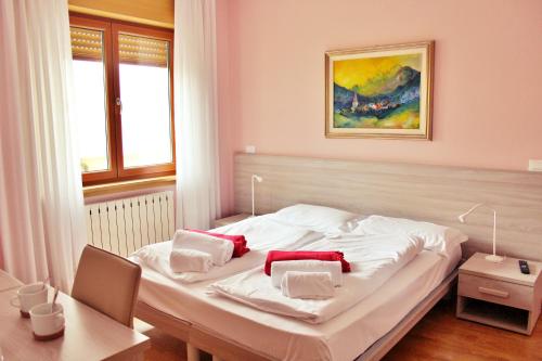 a bedroom with a white bed with red pillows on it at Adriatico Rooms in Tarvisio