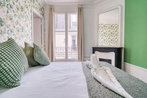 - une chambre avec un grand lit blanc et une cheminée dans l'établissement Green apartment Paris city center, à Paris