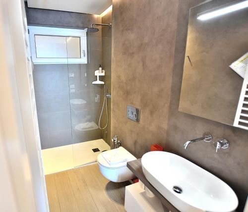 a bathroom with a sink and a toilet and a shower at Leonardo Walsh Apartment With Lake View in Torri del Benaco