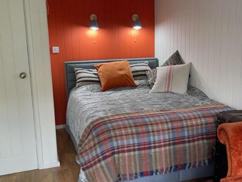 a bedroom with a bed with an orange wall at The Garden Room in Knighton