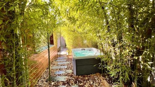 eine Badewanne in einem Garten mit Bäumen in der Unterkunft La Villa Canopée - Piscine chauffée-Fibre-Clim-Jacuzzi in Gujan-Mestras