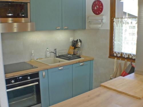 une cuisine avec des armoires bleues et un évier dans l'établissement T3 calme avec balcon, parking et cave à 500m du centre - FR-1-629-57, à Samoëns