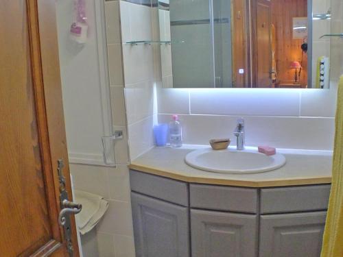 une salle de bain avec un lavabo et un miroir dans l'établissement T3 calme avec balcon, parking et cave à 500m du centre - FR-1-629-57, à Samoëns