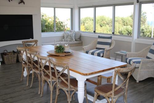 una sala da pranzo con tavolo e sedie in legno di Ocean Pearl Hermanus - 5 Bedrooms a Hermanus