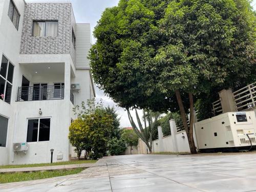 an empty street in front of a house with a tree at AlanVal Apartments in Accra