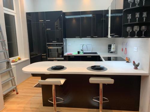 una cucina con mobili neri e un'isola bianca con sgabelli di Budapest, Graf Teleki Laszlo Appartement a Budapest