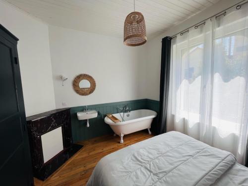 een badkamer met een bad, een wastafel en een bed bij Maison des années 1920 - à 150 m de l'océan et proche des commodités - 4 logements indépendants in Saint-Jean-de-Monts