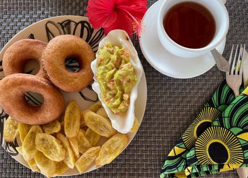 a plate of food with donuts and a cup of tea at Max Hotel Nungwi in Nungwi