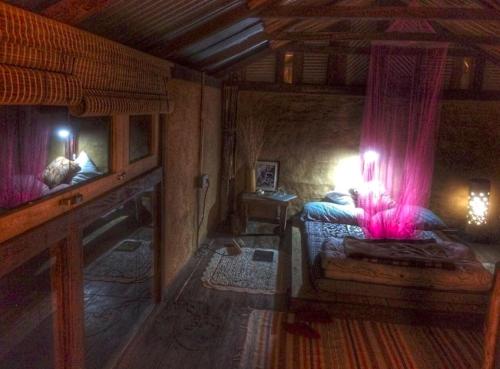 een slaapkamer met een bed met roze gordijnen in een kamer bij Petrichor - Regenerative Living Experience in Gorubathān