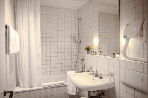 Baño blanco con lavabo y espejo en Hotel Loge, en Winterthur