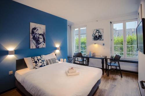 a bedroom with a large bed with a blue wall at Hotel Loge in Winterthur