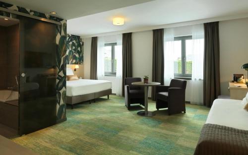 ワーテルローにあるル　コテ ヴェールのベッド、テーブル、椅子が備わるホテルルームです。