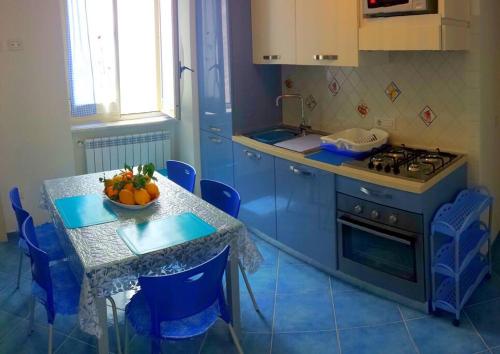 una cucina con armadi blu e un tavolo con un cesto di frutta di Casa Vacanze La Rosa Del Mare ad Amalfi