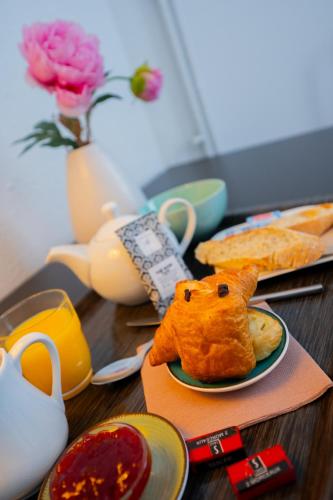a wooden table with a plate of food and tea pots at Hôtel & Restaurant des Remparts in Rochefort