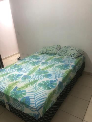 a bed with a blue and green comforter on it at Odil in Praia Grande