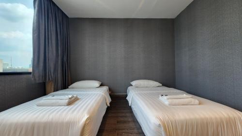 two twin beds in a room with a window at Happy Station Bangkok in Bangkok