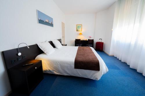 a bedroom with a large bed and a desk at Hôtel & Restaurant des Remparts in Rochefort