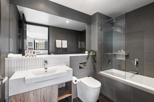 een badkamer met een wastafel, een toilet en een bad bij Quest Geelong Central in Geelong