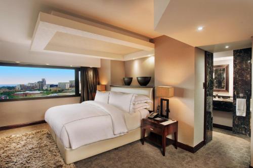 a bedroom with a large white bed and a window at Sandton Sun and Towers in Johannesburg