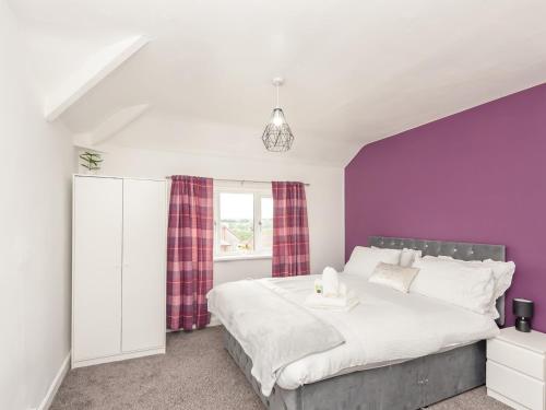 1 dormitorio con 1 cama grande y pared morada en Pass the Keys Large Family Getaway, en Leeds
