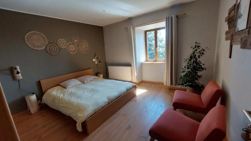 a bedroom with a bed and a chair and a window at Grange De Sagne maison et table d hôtes avec dîner sur réservation in Saint-Jean-Roure