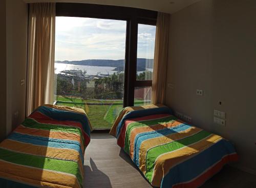 - 2 lits dans une chambre avec une grande fenêtre dans l'établissement Casa con vistas al mar en Pontevedra, à Pontevedra